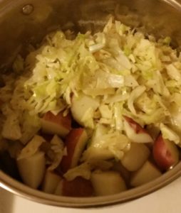 chopped potatoes in a pot with sautéed vegetables on top