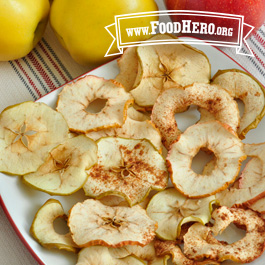 baked apple chips on a plate next to fresh apples