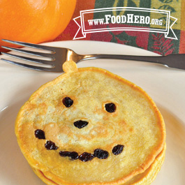 plate of jack-o-lantern pumpkin pancakes with raisins creating a smiling face