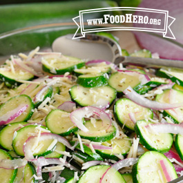 zucchini salad in a glass serving bowl with silver spoon