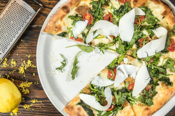 pizza with fresh seasonal greens, tomatoes and shredded cheese