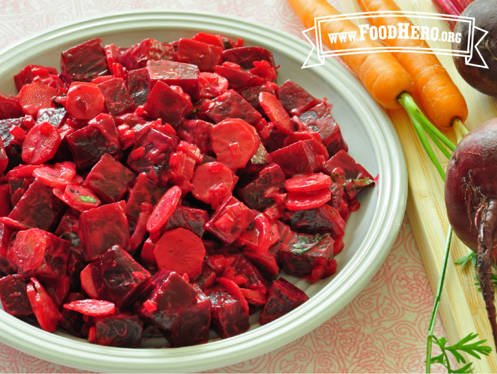 bowl of beet and carrot salad with 2 fresh carrots next to it