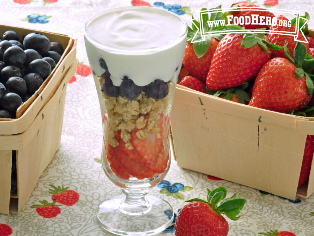 parfait glass of berry blast off with boxes of strawberries and blueberries
