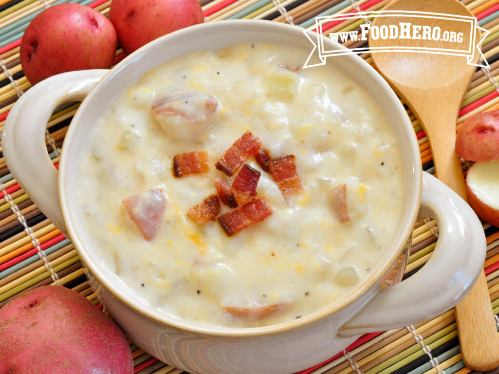 bowl of cheesy potato soup next to fresh potatoes