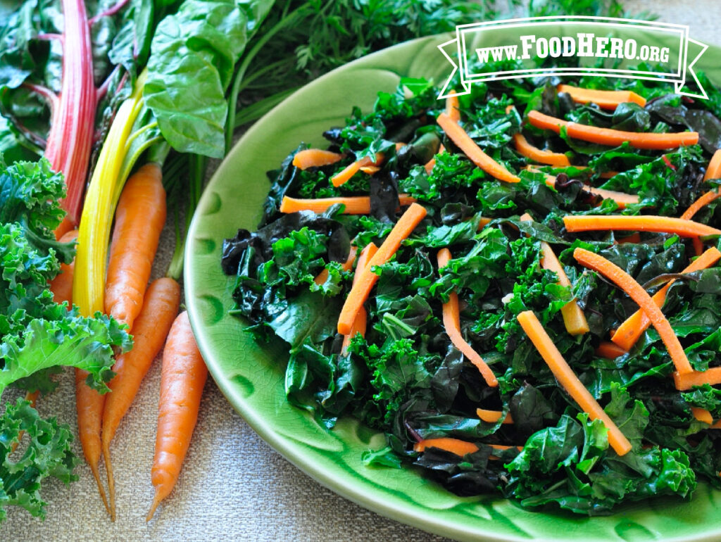 dish of greens with carrots next to fresh carrots