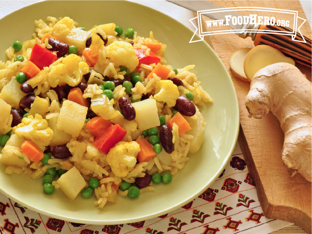 individual bowl of vegetable and rice skillet meal next to a chopping board with chopped ginger