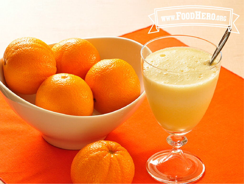 glass of orange delight next to bowl of oranges