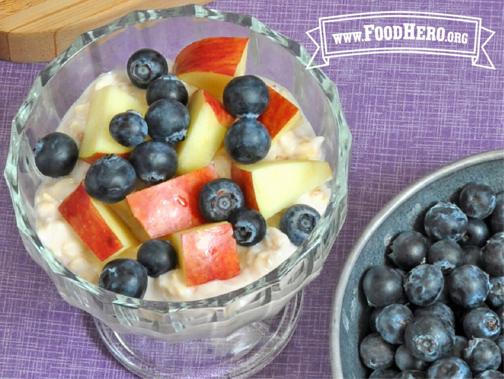 bowl of overnight oatmeal next to bowl of fresh blueberries