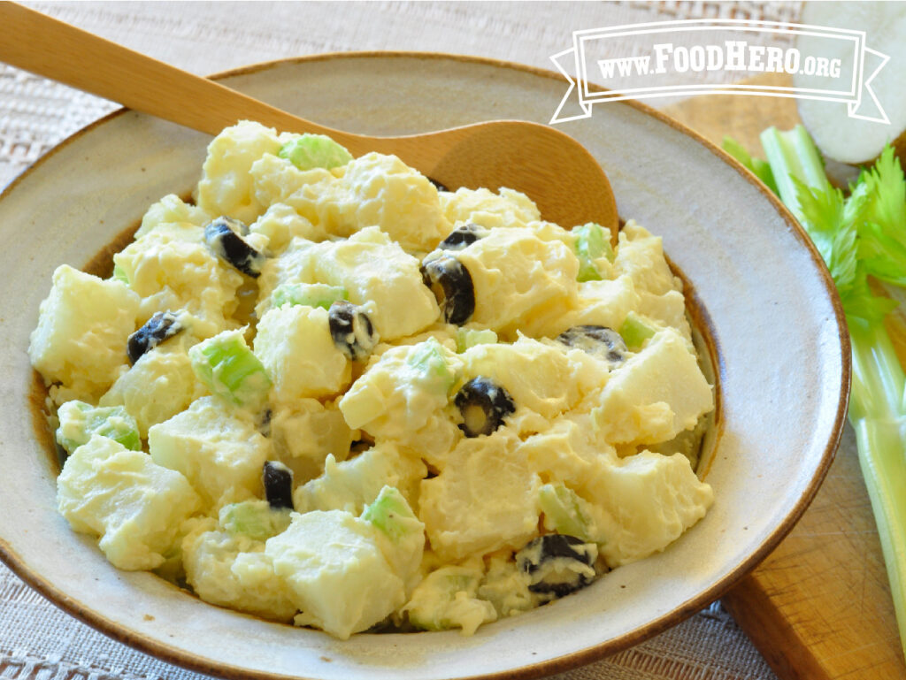 bowl of potato salad with wooden serving spoon