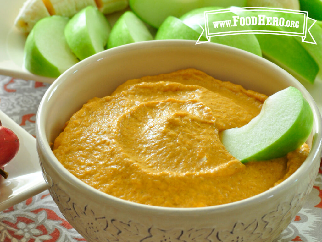 bowl of pumpkin fruit dip with sliced green apples