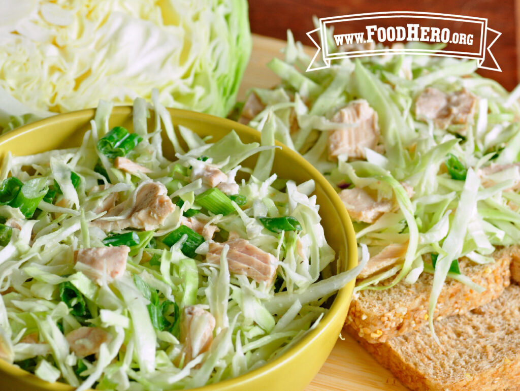tuna cabbage salad in a bowl next to a head of fresh cabbage