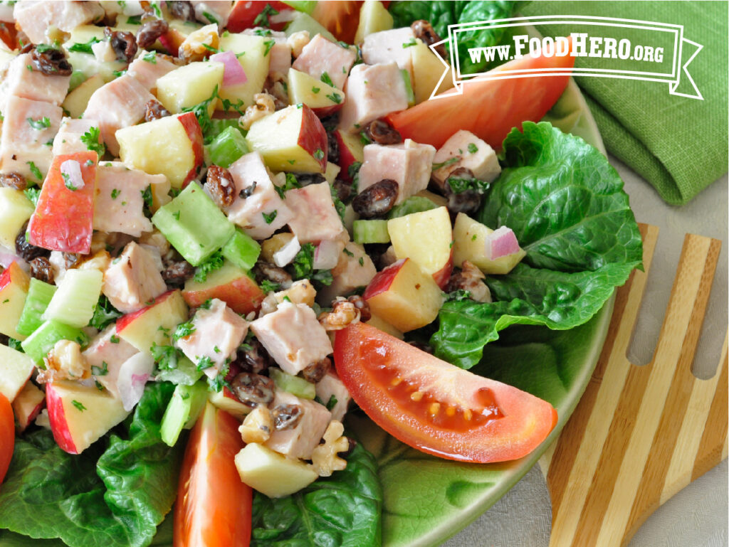 bowl of turkey salad next to wooden fork and napkin