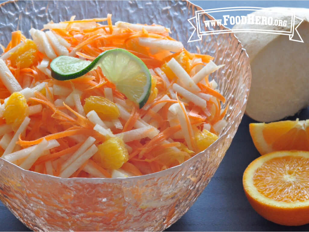 carrot, jicama and orange salad next to fresh cut orange