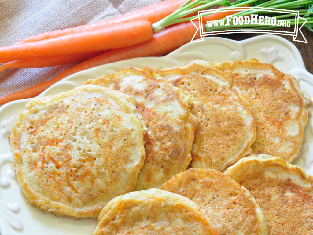 plate of carrot pancakes next to a bunch of fresh carrots