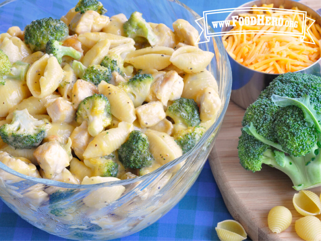 bowl of chicken, broccoli and cheese next to fresh broccoli head