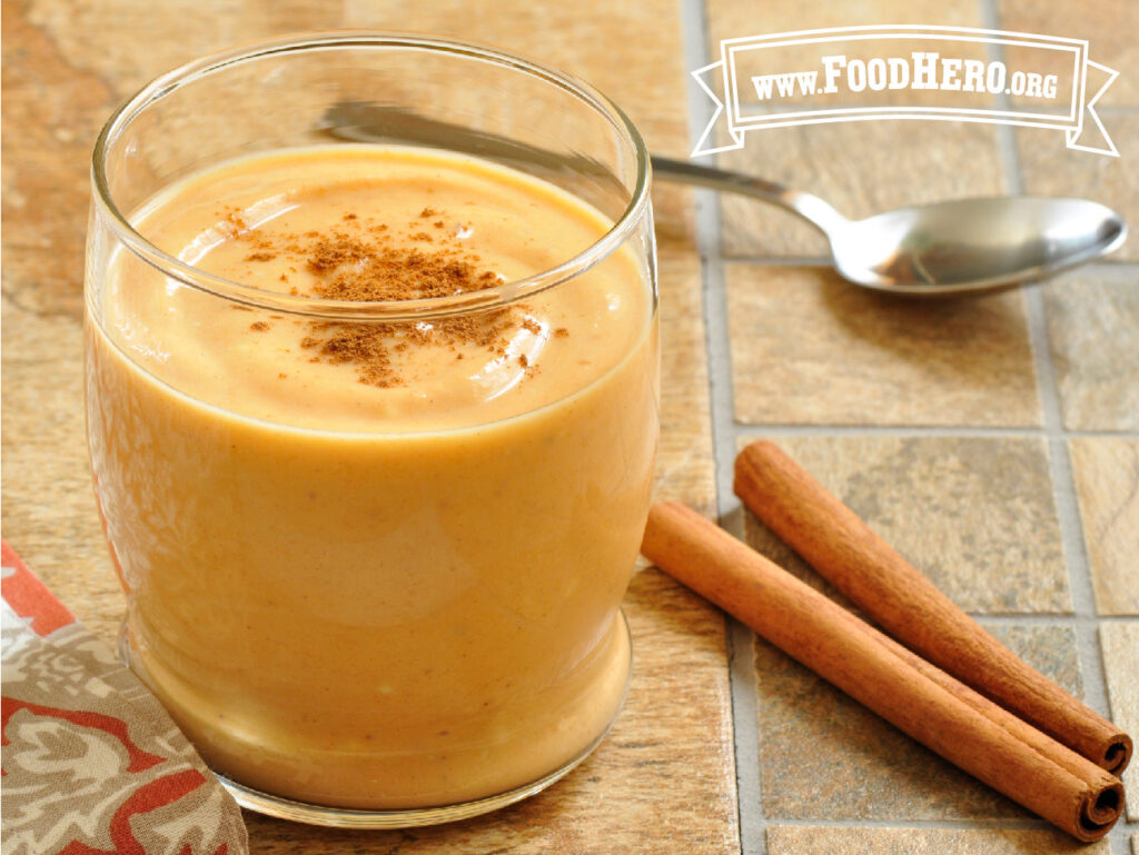 pumpkin smoothie in a glass with 2 sticks of cinnamon