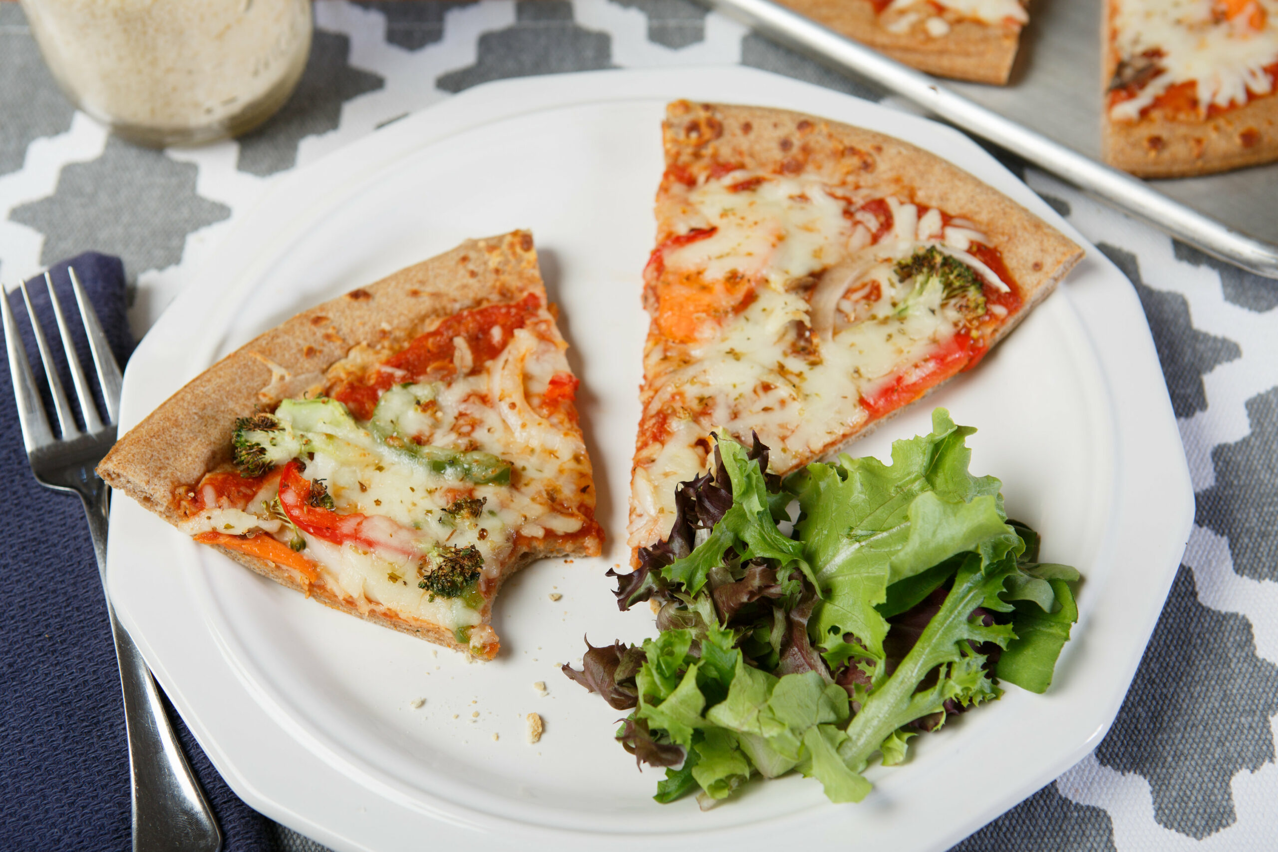 plate with roasted vegetable pizza and salad