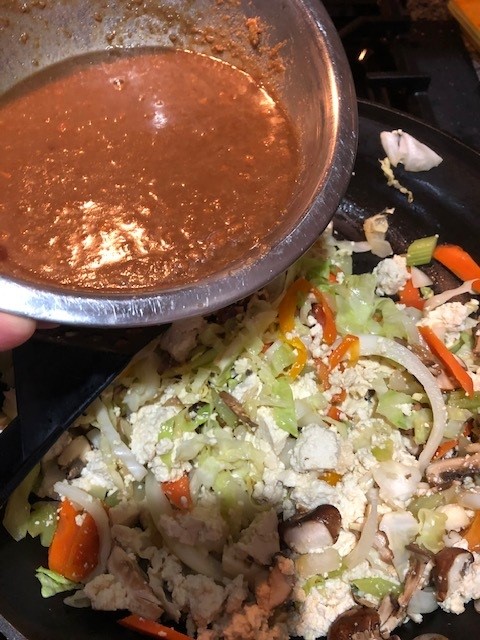 adding sauce to cooked tofu and veggies